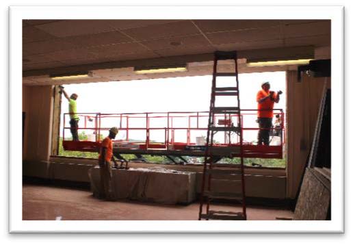 Workers reconstructing window frames to allow for the installation of new windows.